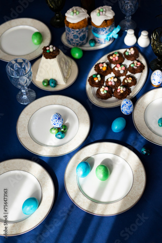 Holiday table laid for Easter celebration with Easter cakes, cookies in shape of nests, tradition cottage cheese Easter and colorful hand-pained Easter eggs