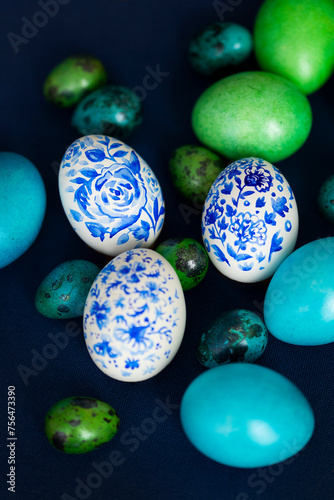 Hand-painted blue and white and green Easter eggs on dark blue tablecloth