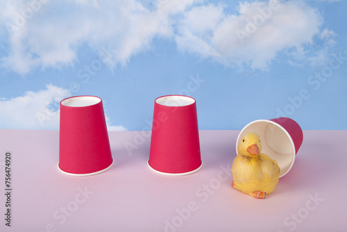 Three paper cups are used to play the game of bonneteau and a duck under one cup