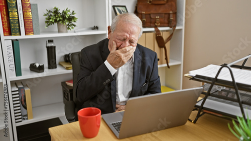 Canvas Print The struggle is real - senior business man forced to work sick at the office, displaying flu symptoms while slouched at his desk, amidst the deafening indoor silence