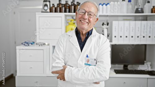 Smiling senior man  a confident scientist  standing with arms crossed in a lab  working on exciting medical research amidst test tubes and microscopes. a relaxed expression of joy in science 
