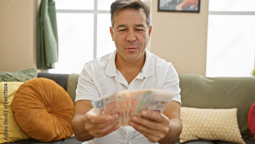 Middle-aged man counting singapore dollars in a cozy living room, illustrating finance at home. Middle-aged man counting singapore dollars in a cozy living room, illustrating finance at home.