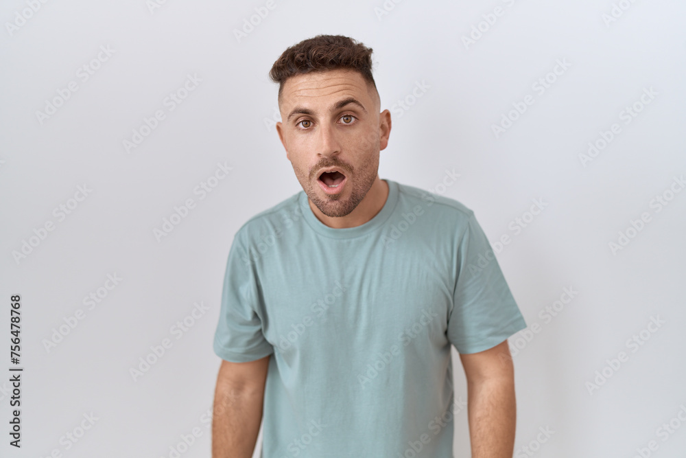 Hispanic man with beard standing over white background afraid and shocked with surprise and amazed expression, fear and excited face. Hispanic man with beard standing over white background afraid and shocked with surprise and amazed expression, fear and excited face.