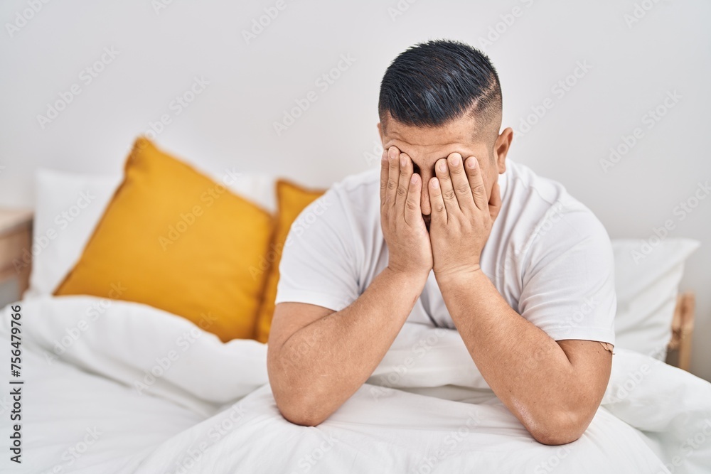 Young latin man stressed sitting on bed at bedroom Young latin man stressed sitting on bed at bedroom