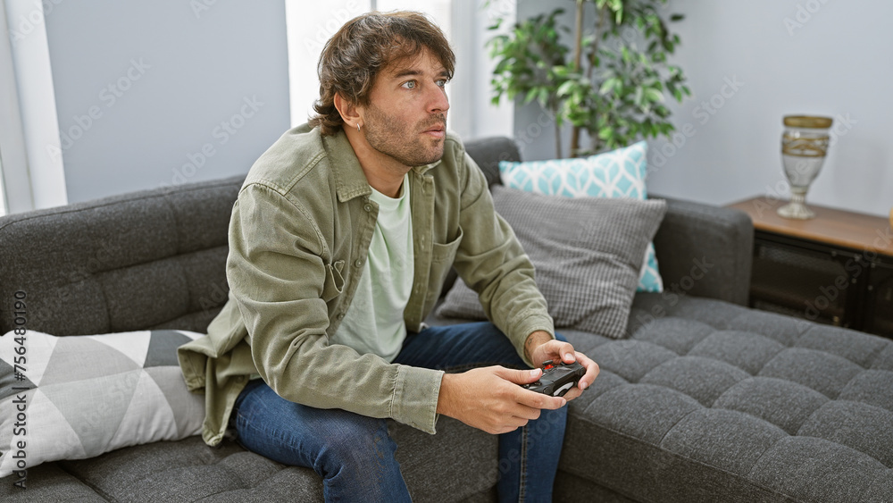 Handsome caucasian man lounging on sofa playing video games in a modern living room setting