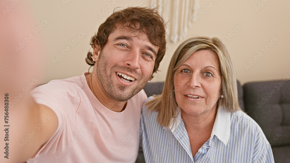 Joyful mother and son, together on the living room sofa, making a sweet selfie with a confident smile. creating happy life memories at their cozy home. Joyful mother and son, together on the living room sofa, making a sweet selfie with a confident smile. creating happy life memories at their cozy home.