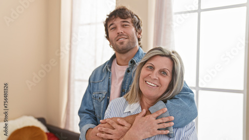 Confident mother and son share a warm, smiling hug indoors, enjoying their love-filled, casual lifestyle in their happy home. © Krakenimages.com