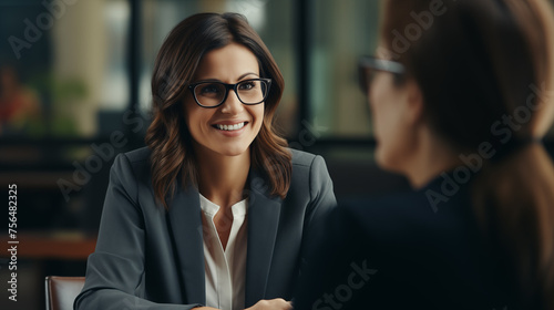 Professional businesswoman in a meeting with a colleague, smiling and engaging in conversation.
