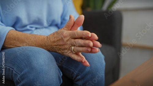 Elderly woman's hands with wedding ring in a casual home setting, implying leisure, comfort, and relaxation.