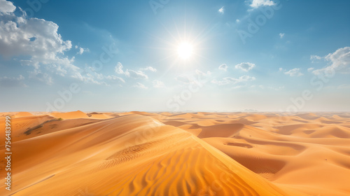 Scenic view of vast desert dunes with patterns of wind-swept sand under a bright sun in a cloud-dappled blue sky.