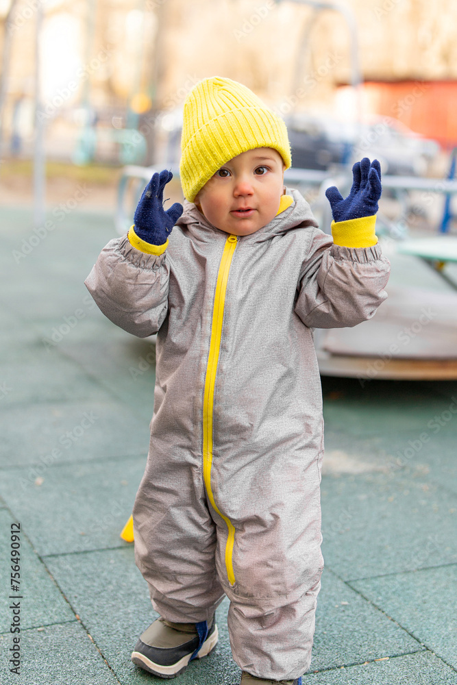 Baby playing on the playground in warm overalls. Outdoor games in cold weather. Baby playing on the playground in warm overalls. Outdoor games in cold weather.
