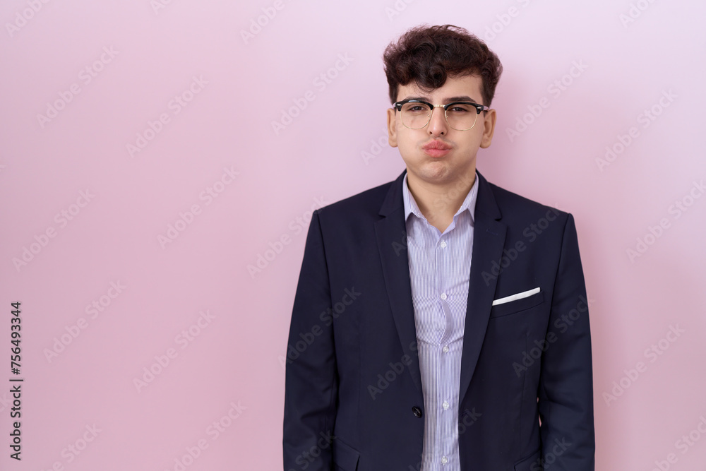 Young non binary man with beard wearing suit and tie puffing cheeks with funny face. mouth inflated with air, crazy expression. Young non binary man with beard wearing suit and tie puffing cheeks with funny face. mouth inflated with air, crazy expression.