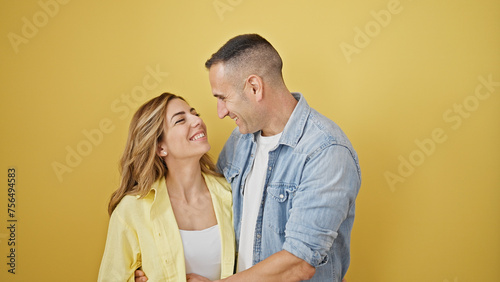 Man and woman couple hugging each other smiling over isolated yellow background © Krakenimages.com