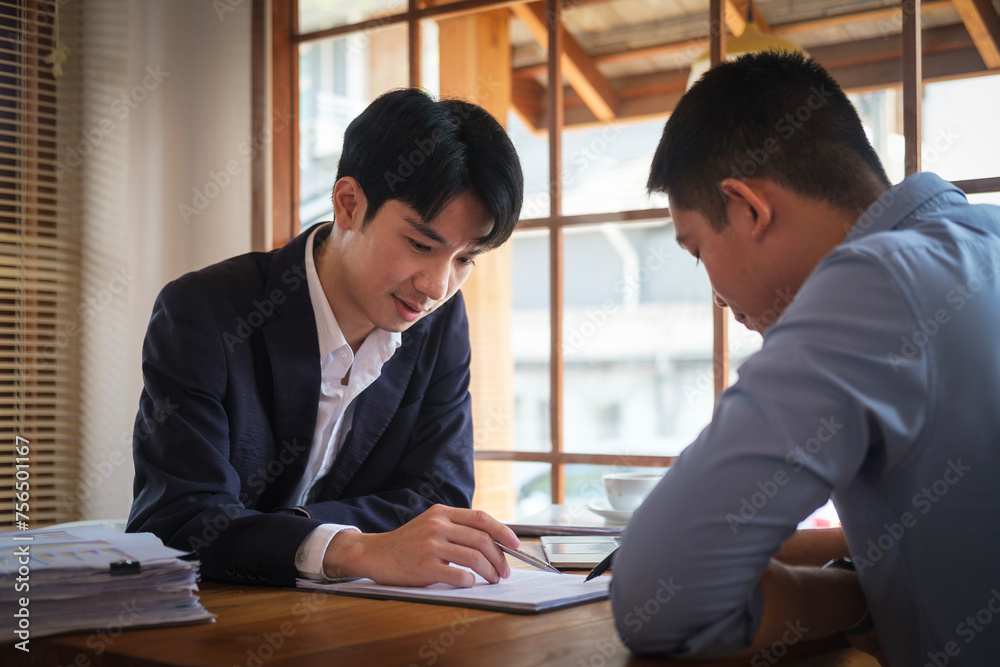 Concentrated male insurance agent discuss paper policy terms conditions with his client at meeing. Concentrated male insurance agent discuss paper policy terms conditions with his client at meeing.