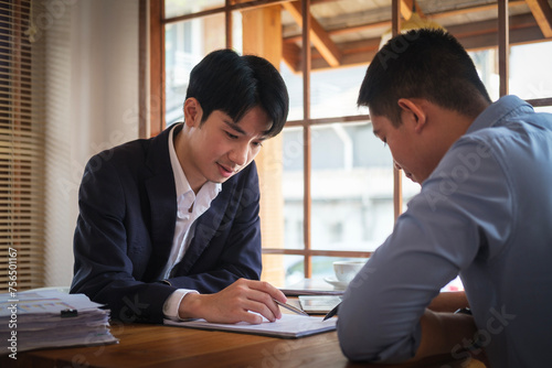 Concentrated male insurance agent discuss paper policy terms conditions with his client at meeing.