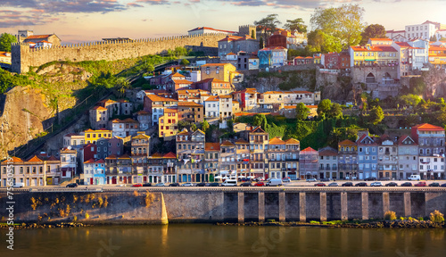 Antique town Porto, Portugal. Sunset sun over silhouettes skyline of porto city roofs houses along river © Yasonya
