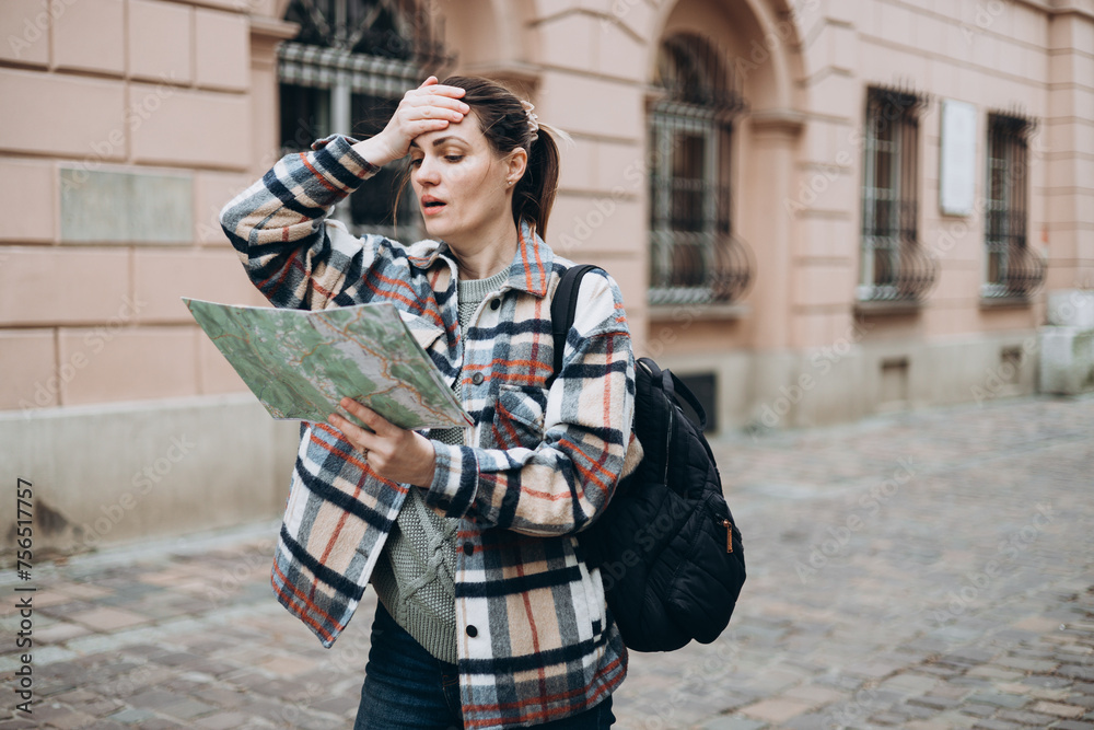 Portrait beautiful woman with paper map on urban street. Young worried female traveler using map lost in the city. Vacation concept by exploring interesting places to travel.