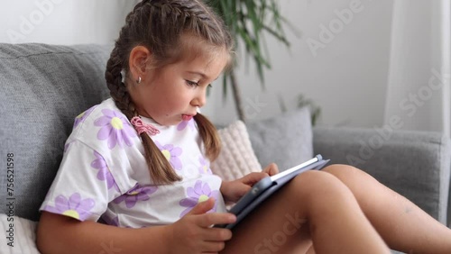 Adorable little girl use tablet at home. Five year old girl play games on tablet