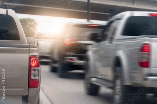 Rear side view of pickup car driving on the road. Other cars driving pass fast speed on the road. During traffic struck in Thailand. Background with concrete bridge with light under from the sky.