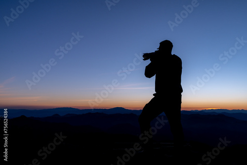 The silhouette of a tourist taking a photo at the top of the mountain
