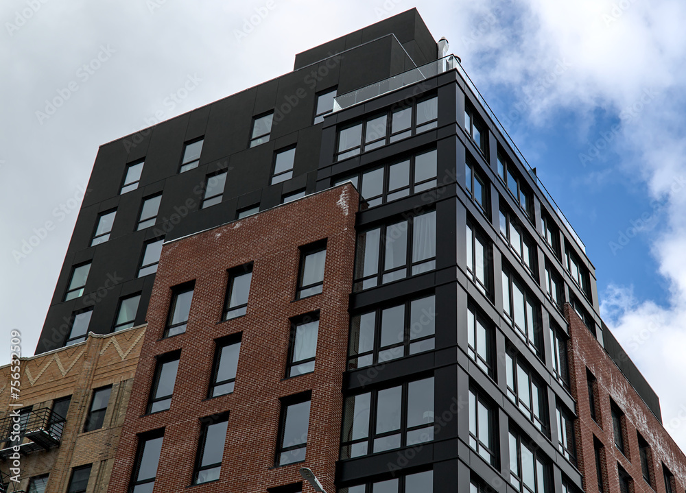 modern residential apartment building in brooklyn, new york (luxury condo high rise real estate units) co-op housing detail (windows reflecting sky, clouds) urban dwelling home new construction