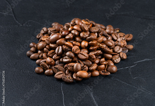 Small pile of roasted arabica coffee beans close-up on dark background