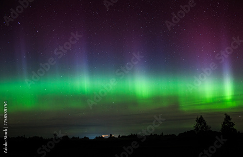 Northern lights against the background of the starry sky, green rays, pink shades, bright stars, night.