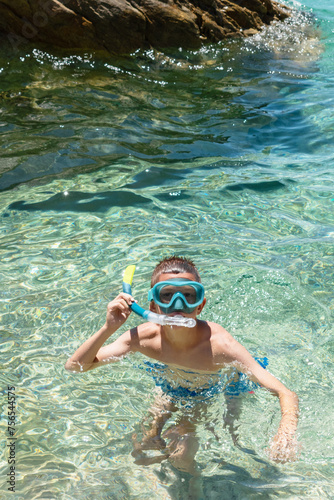 Boy with snorkel and mask in crystal clear sea water, enjoying beach family vacation and active summer holiday. Snorkeling, swimming, water sports concept