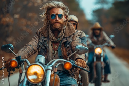 Three bikers cruise down a dusty forest road, the lead biker in focus