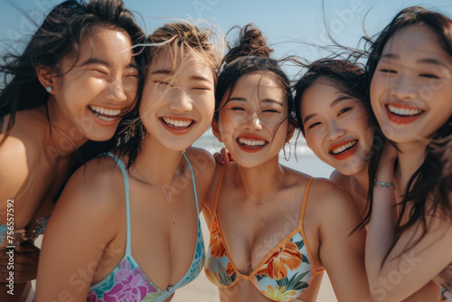 Group of smiling laughing young asian women, wearing swimsuits looking at the camera