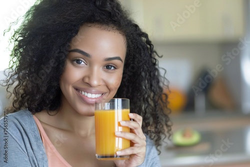 Healthy Nutrition. Cheerful African American Woman Drinking Fresh Orange Juice Holding Glass And Smiling To Camera Sitting At Dining Table In Modern Kitchen At Home. Weight Loss Diet Concept