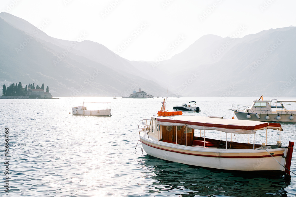 Moored excursion boats and motorboats at sea against the backdrop of the islands of the Bay of Kotor. Perast, Montenegro
