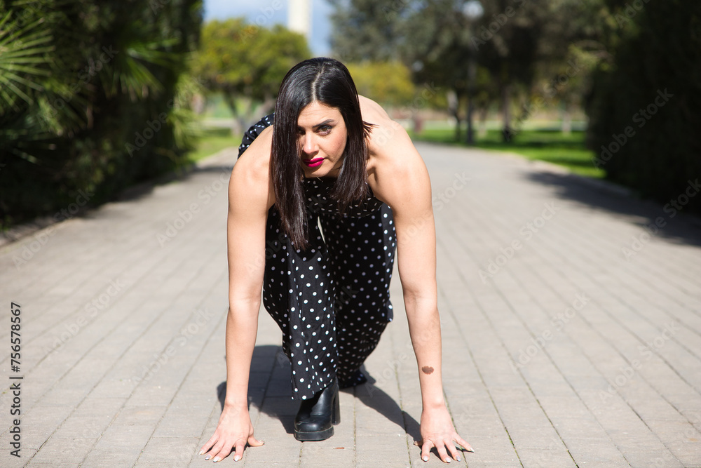 Young and beautiful business woman, brunette and black dress with white polka dots ready to start running. Concept of starting a professional career and empowered woman. Young and beautiful business woman, brunette and black dress with white polka dots ready to start running. Concept of starting a professional career and empowered woman.