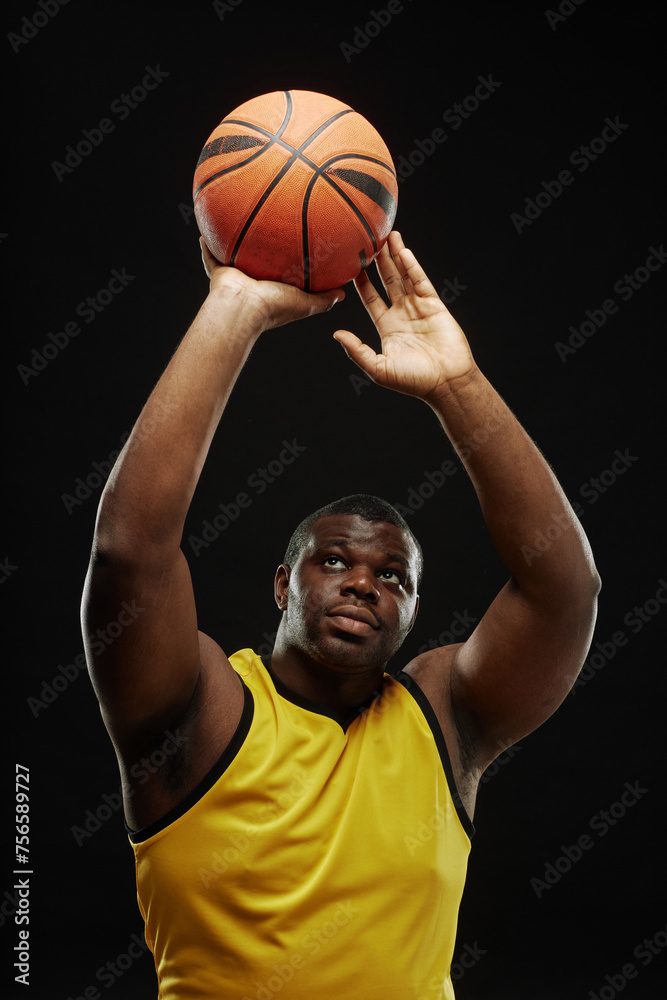 Vertical portrait of African American basketball player passing ball against black background