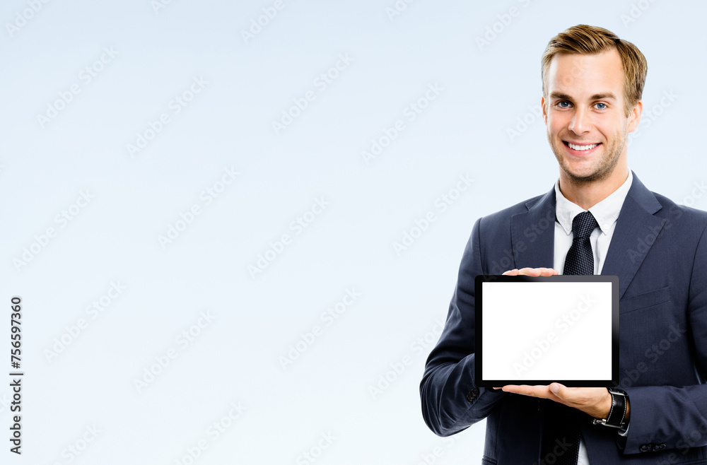 Happy smile business man wear suit, necktie showing advertise tablet pc white screen with ad copy space area, isolated grey background. Studio portrait image - businessman holding touchpad computer. Happy smile business man wear suit, necktie showing advertise tablet pc white screen with ad copy space area, isolated grey background. Studio portrait image - businessman holding touchpad computer.