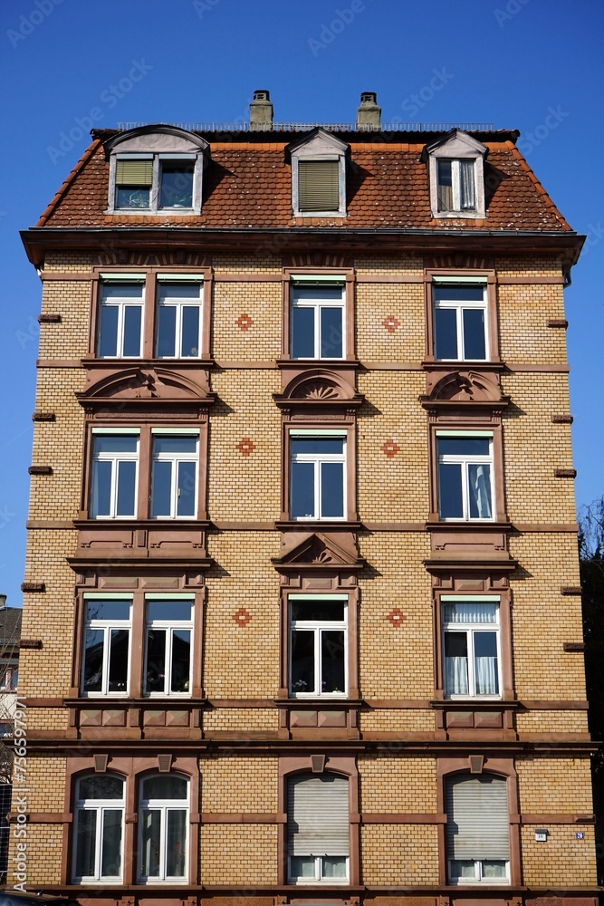 Fototapeta premium Saniertes altes Wohnhaus mit Fassade in Beige, Braun und Naturfarben vor blauem Himmel im Sonnenschein an der Walter-Kolb-Straße im Stadtteil Sachsenhausen in Frankfurt am Main in Hessen