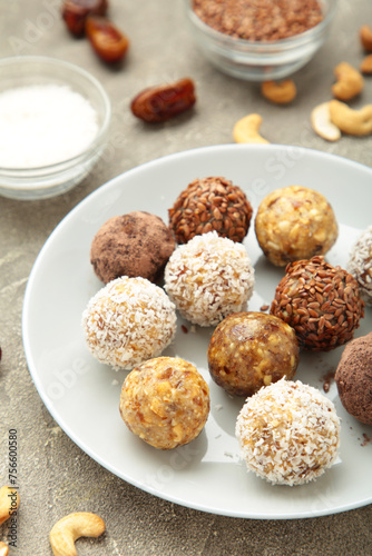 Healthy raw energy balls. Candy vegan balls of dates, nuts and coconut on light background. Top view, concept of useful home-made candies without sugar. Vertical photo