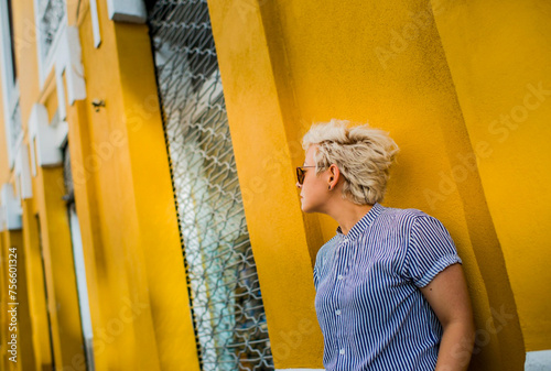 mujer rubia casual apoyada en un muro de las calles de la cuidad  photo