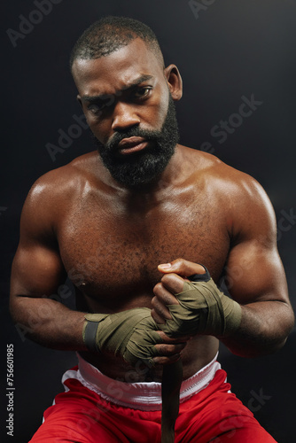 Canvastavla Vertical portrait of tough muscular boxer looking at camera while wrapping hands