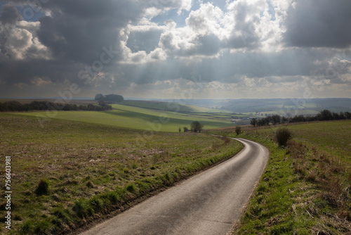 Empty single track country lane running down through open farmland with dramatic sky above, School Lane, East Garston, Berkshire, England, United Kingdom, Europe