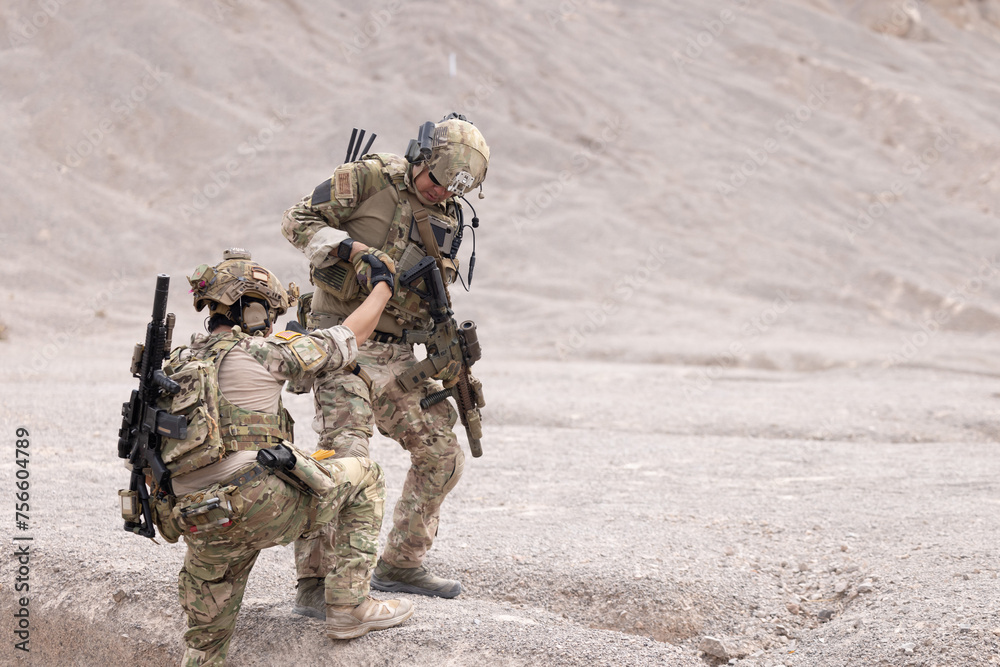 Soldier giving hand and helping his mate to climb the mountain Soldier giving hand and helping his mate to climb the mountain