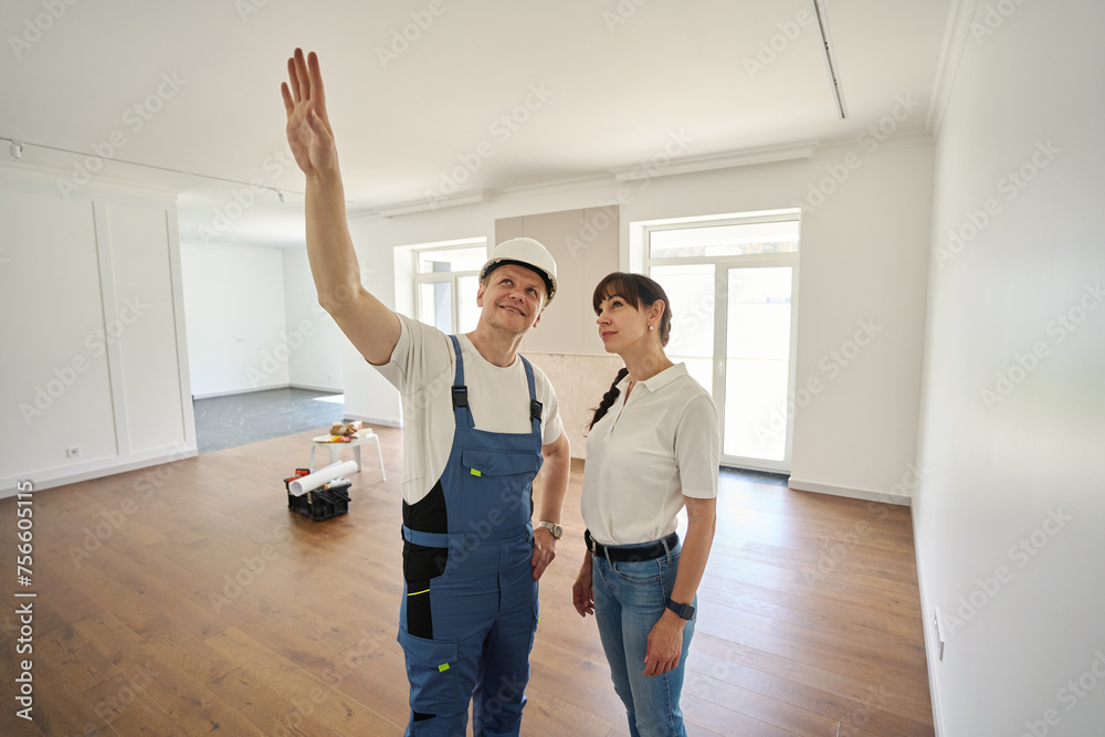 Male worker showing something for woman in new modern townhouse before repair Male worker showing something for woman in new modern townhouse before repair