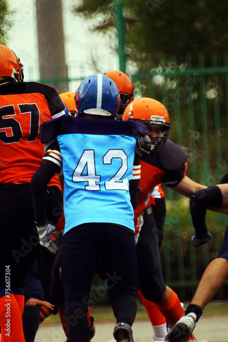 an American football player in a blue and black uniform with the number 42 runs towards his opponents in a black and orange uniform 