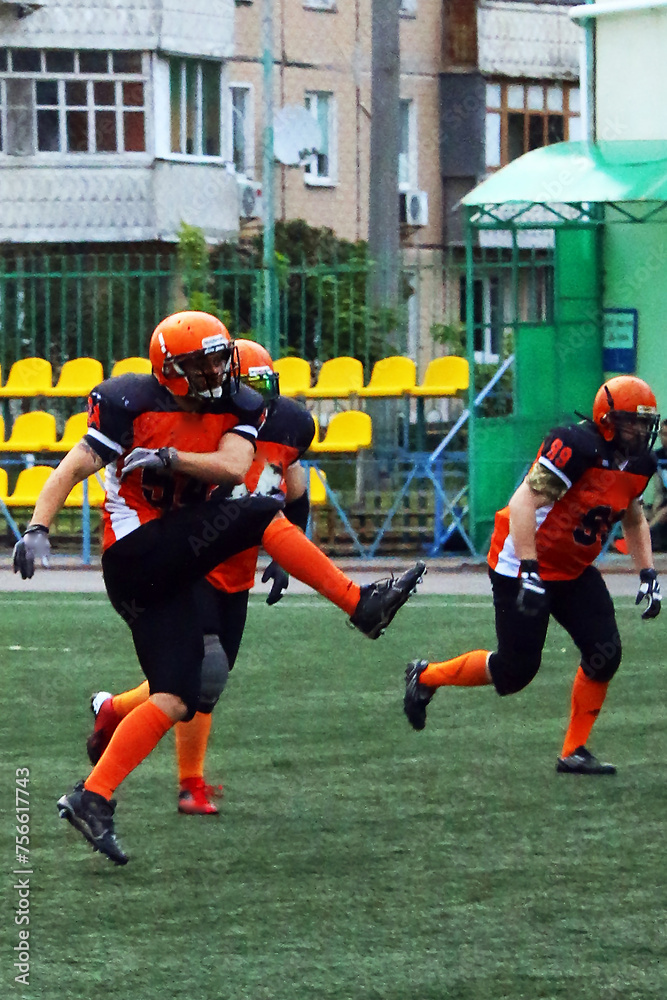 American football player in black and orange uniform raises his leg high while kicking the ball
American football player in black and orange uniform raises his leg high while kicking the ball