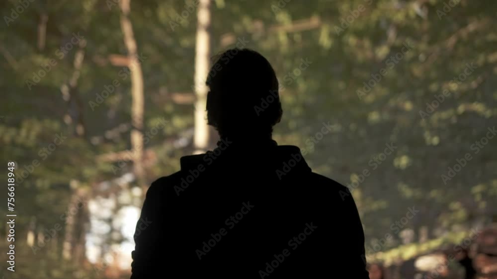 Man wearing virtual reality glasses stands in front of big digital screen with virtual forest graphic visual background, back shot. Man wearing virtual reality glasses stands in front of big digital screen with virtual forest graphic visual background, back shot.