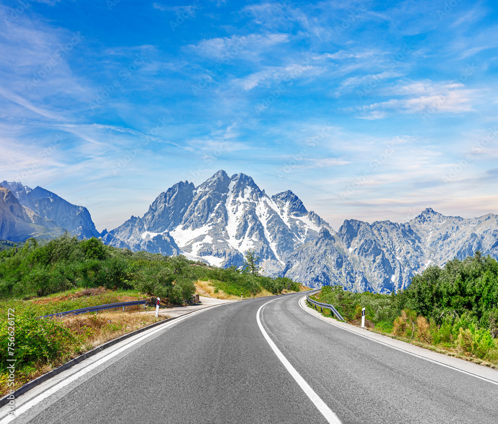 Naklejka premium Country road with rocky mountains in the background.
