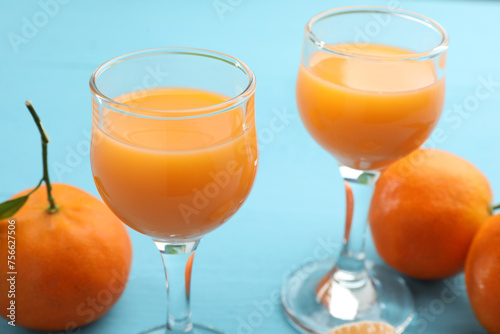Delicious tangerine liqueur and fresh fruits on light blue table, closeup