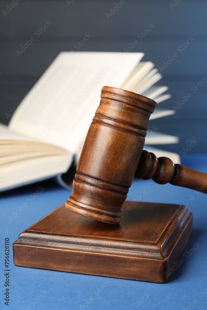 Wooden gavel, sound block and book on blue table, closeup