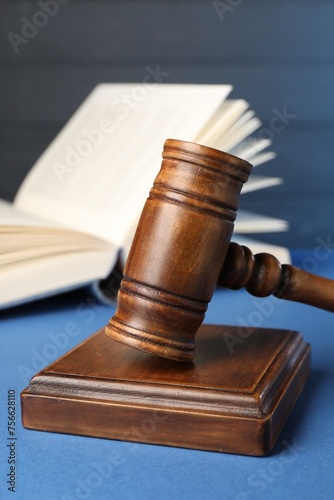 Wooden gavel, sound block and book on blue table, closeup