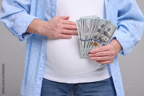 Surrogate mother. Pregnant woman with dollar banknotes on light grey background, closeup